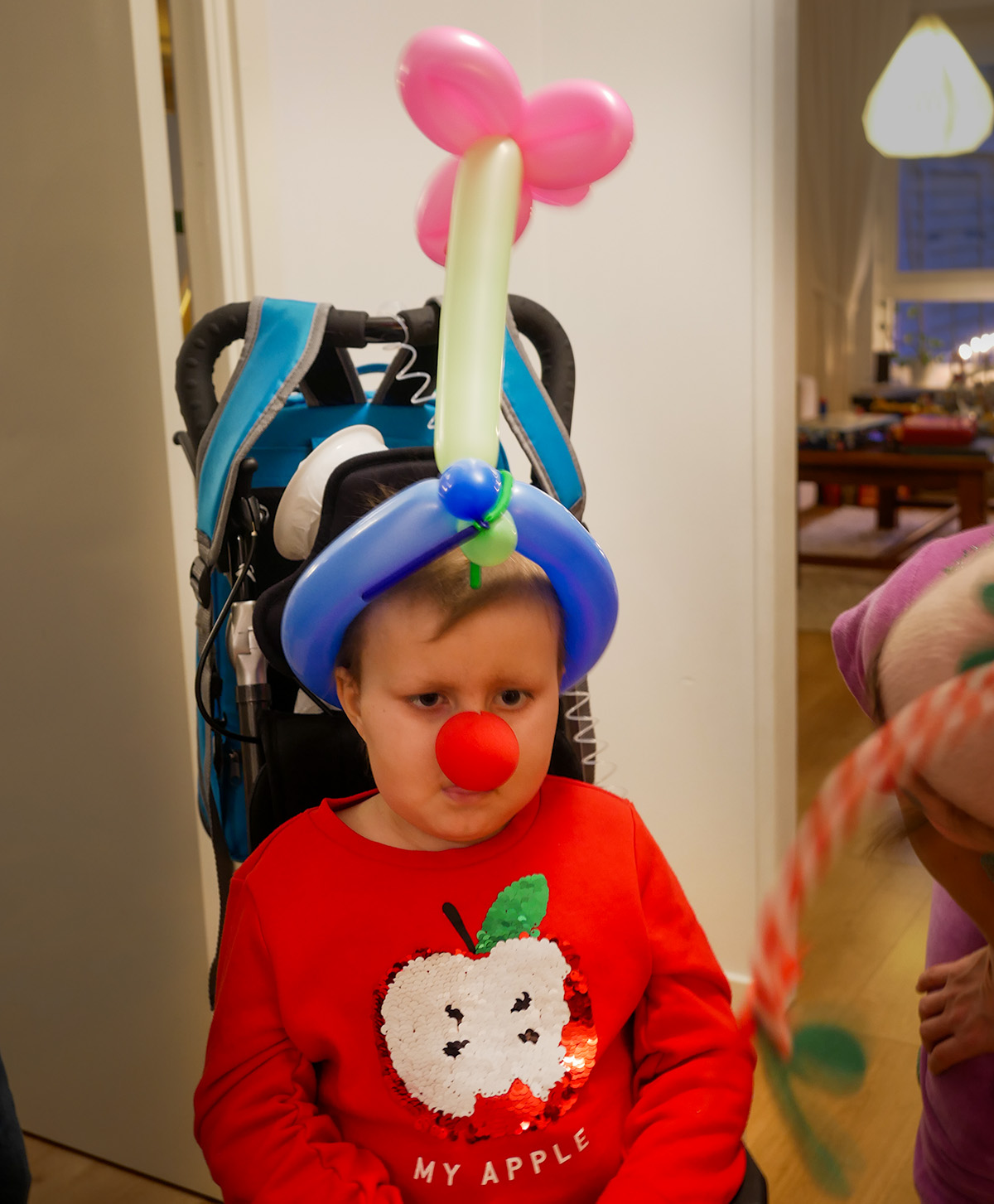 Elis med clownnäsa och en huvudbonad gjord av ballonger.
