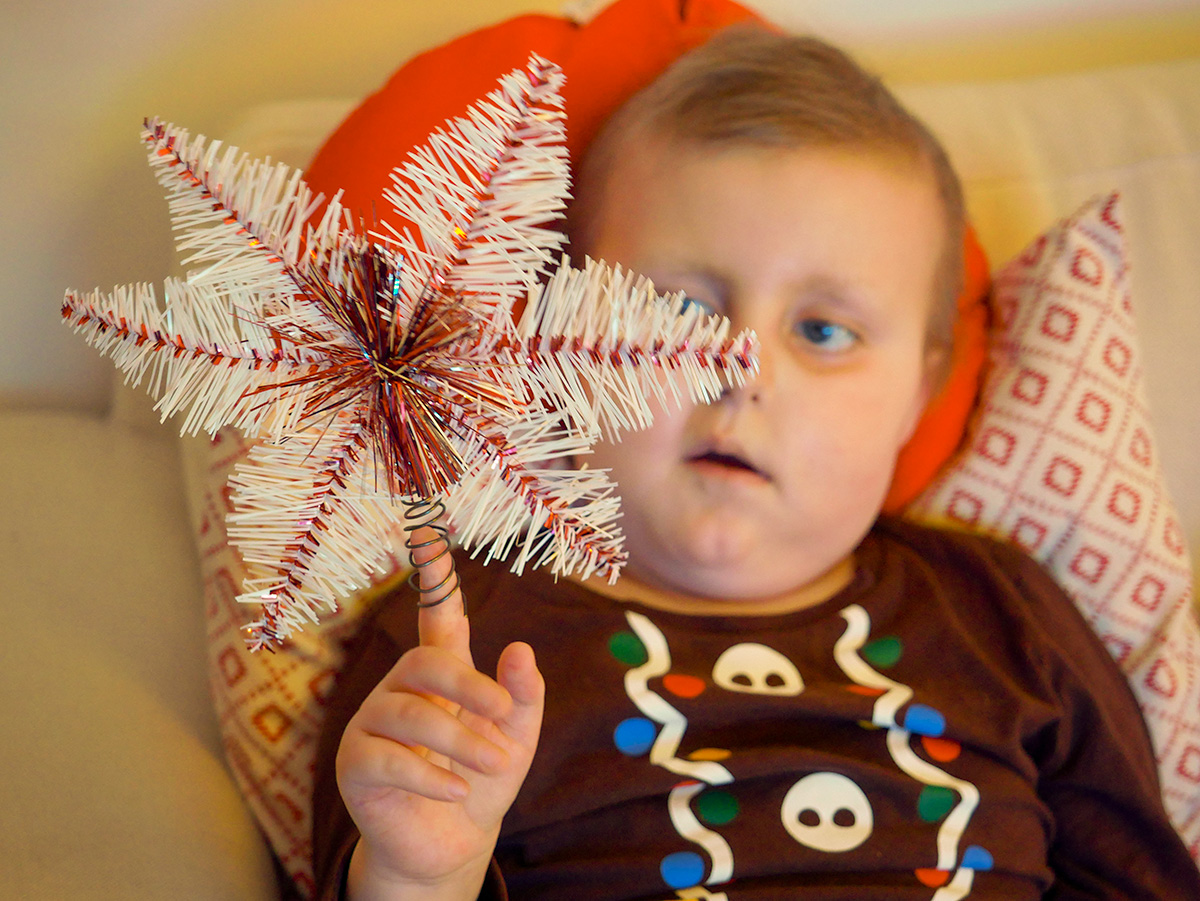 Elis har satt julgranens toppstjärna på pekfingret och leker med den.