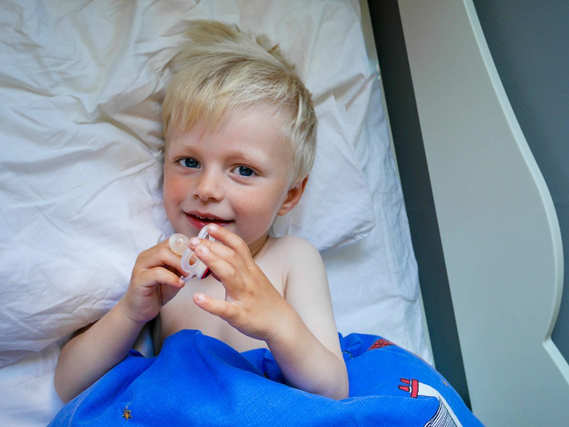 Elis, augusti 2015, i sängen med nappen i handen.