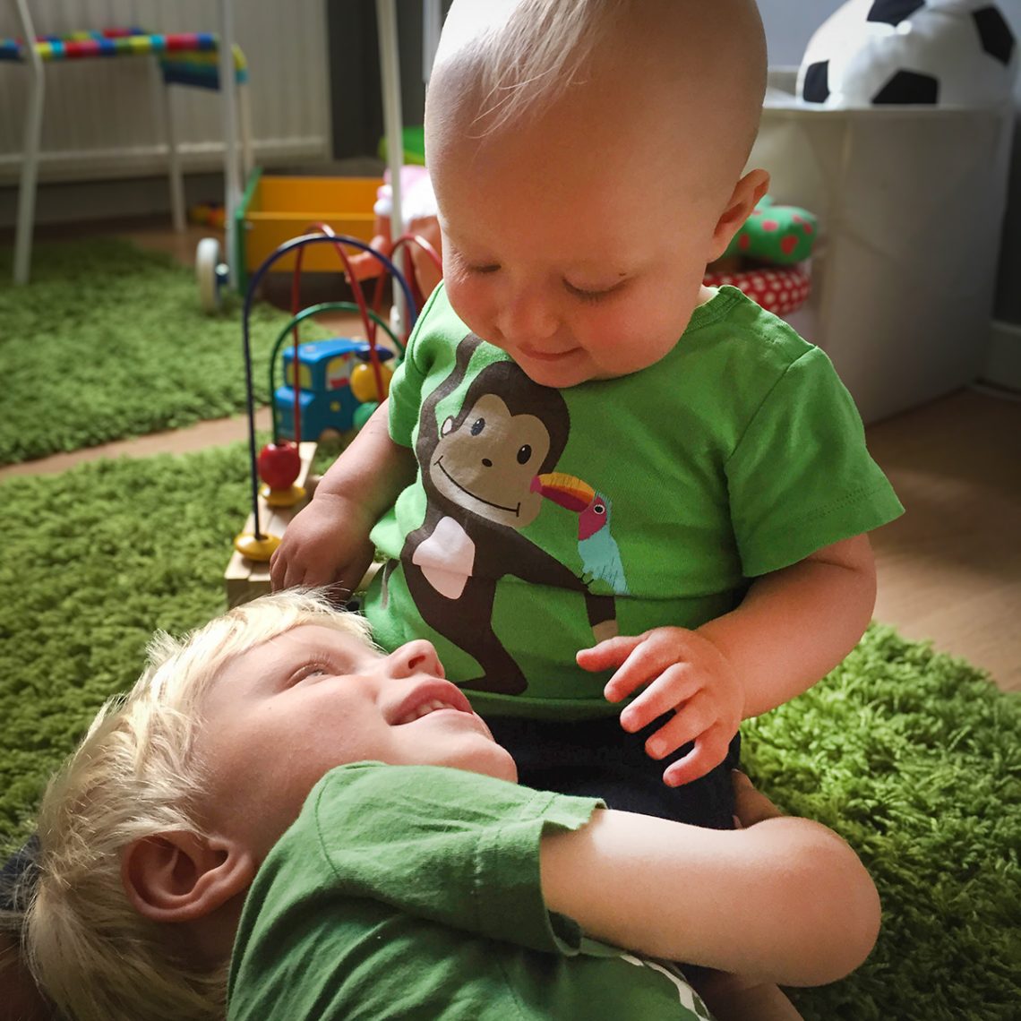 Elis kramar sin lilla lillebror Folke på golvet i lekrummet