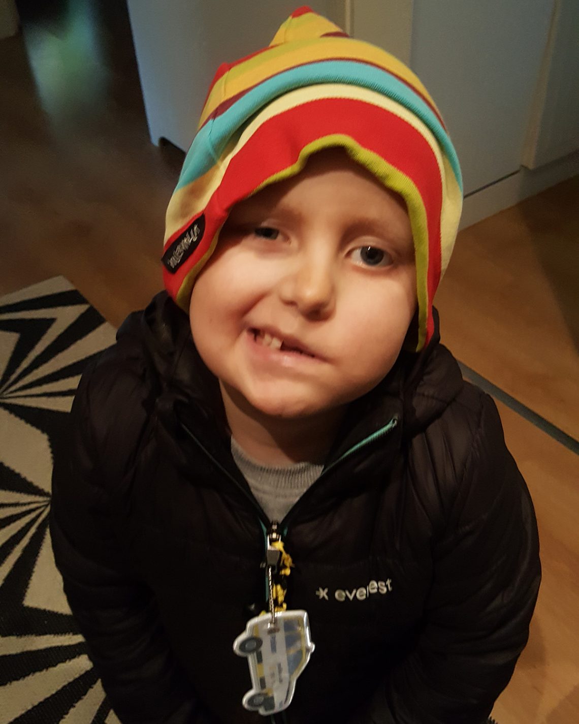 Elis ler mot kameran med en färgglad mössa på huvudet, oktober 2019