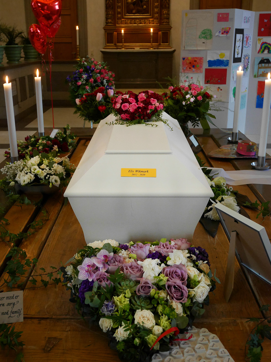 Elis kista omgiven av blommor och ljus