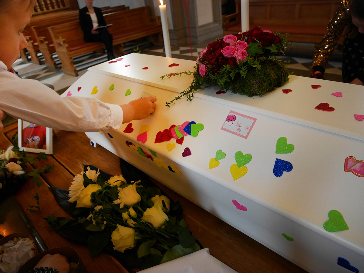 Folke fäster ett klistermärke på Elis kista.