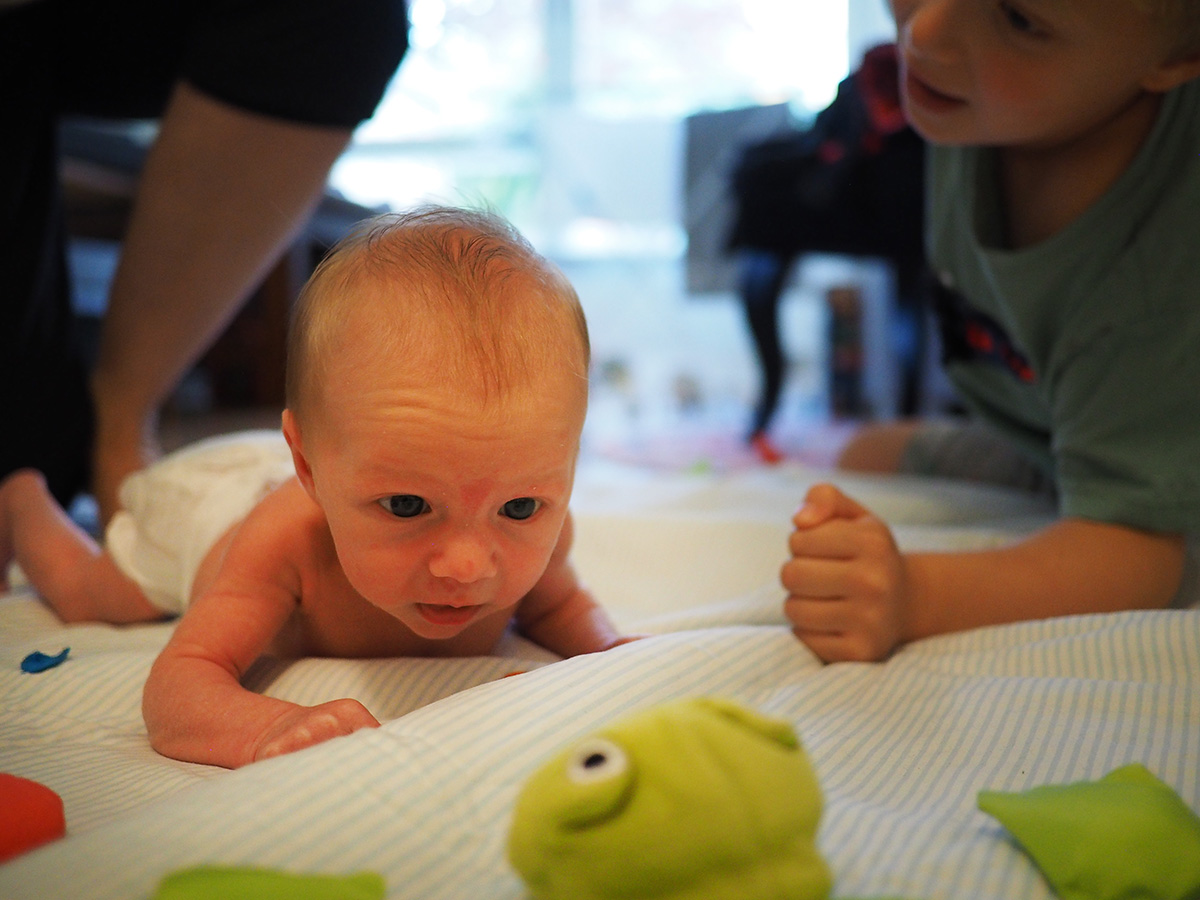 Lillebror kämpar liggande på mage och lyckas lyfta huvudet